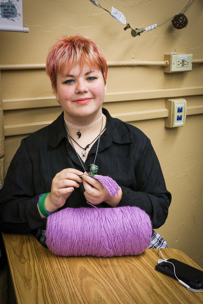 student smiling while crocheting 