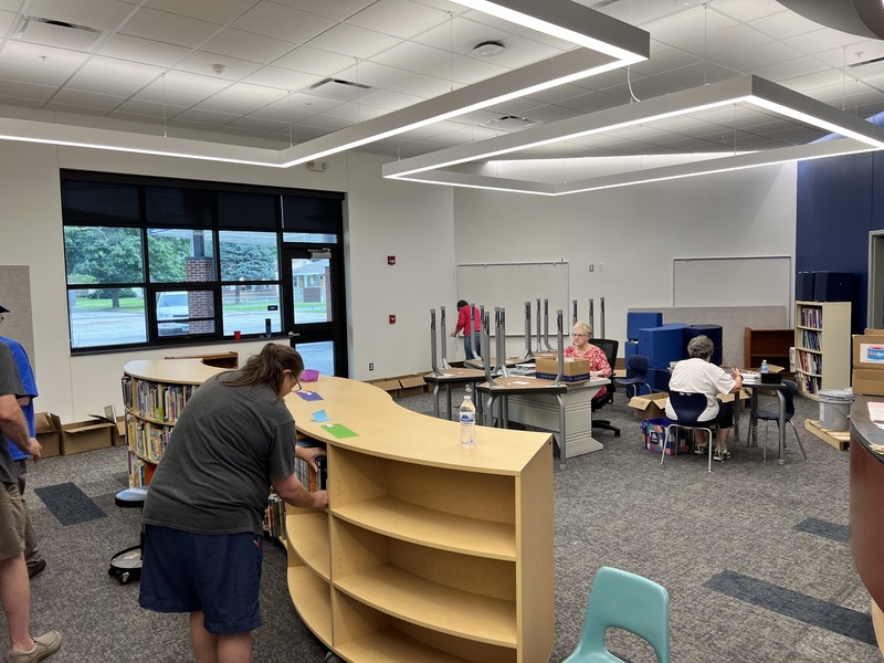 people in library putting books on shelves