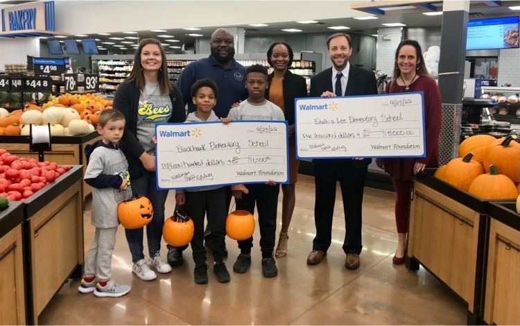 students and staff holding a large check