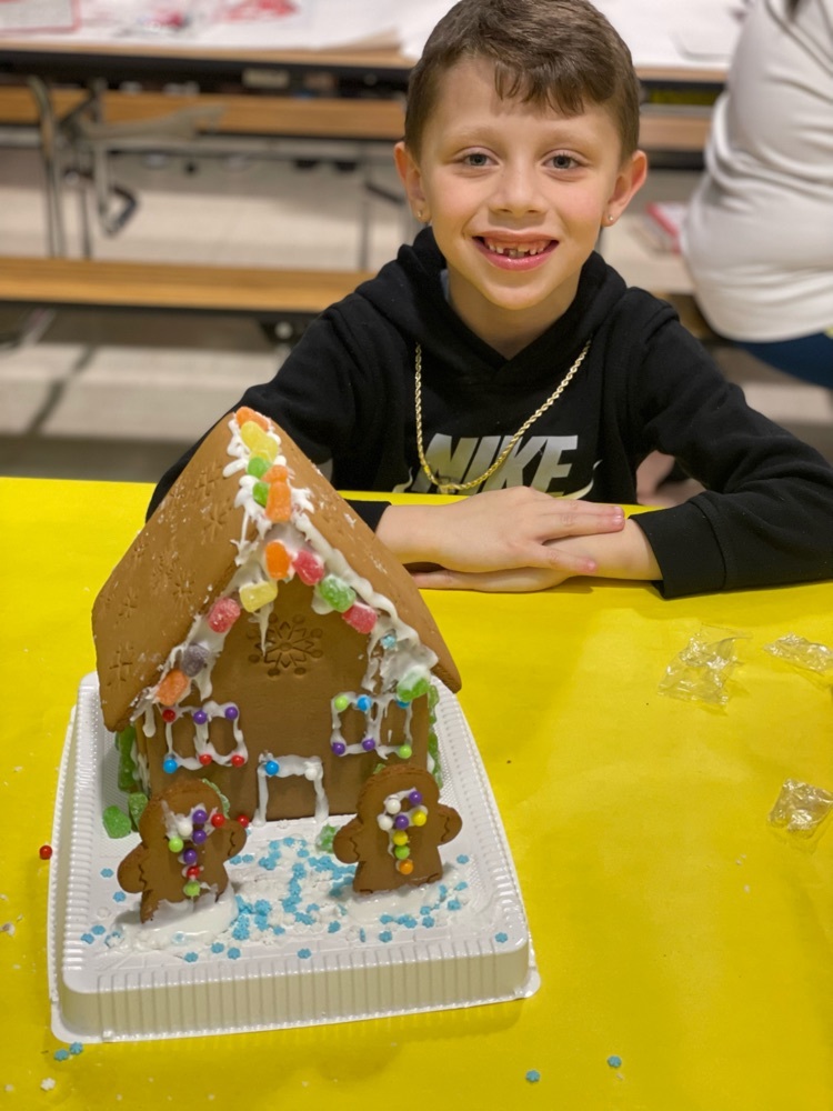 student smiling with gingerbread house 